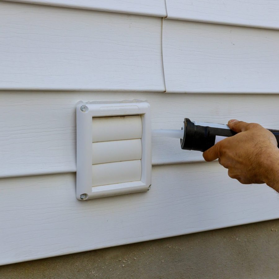 Laundry the white frame of exhaust fan dryer fans with a silicone gun in an apartment building trim